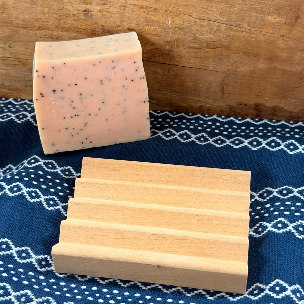 Wooden soap dish with bar of soap beside it
